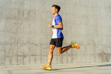 Man Jogging on a Sunny Day Against a Concrete Wall in a City Park