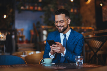 Smiling Businessman Using Smartphone in a Cozy Café Setting