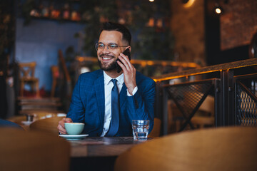 Confident Businessman Enjoying a Phone Call in a Cozy Café