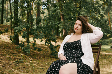 A beautiful plus size woman sits gracefully in a peaceful forest, embracing natures beauty.