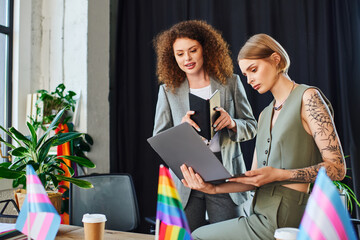 Two coworkers discuss a project together, embracing inclusivity and diversity in their workspace.