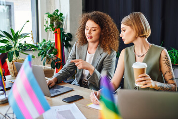 Colleagues share ideas over laptops while celebrating diversity in their workspace.