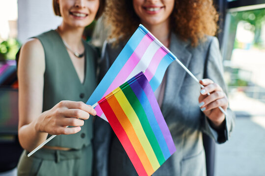 Two coworkers joyfully display pride flags, symbolizing inclusivity and support at work.