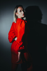 A woman in a red dress is standing in front of a wall