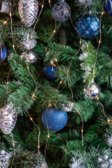 Christmas tree with blue and silver toys. Festively decorated Christmas tree with garlands. Symbol of the new year in trend colors