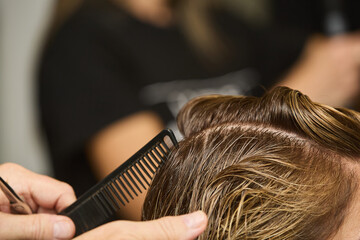 Fototapeta premium Rome, Italy - 10 31 2024 Detail of a women's hairstyle as it is being arranged for a cut, with wet, well-combed hair in a beauty salon
