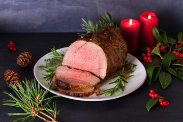 Whole round roast beef and Christmas decorations. New Year dinner table