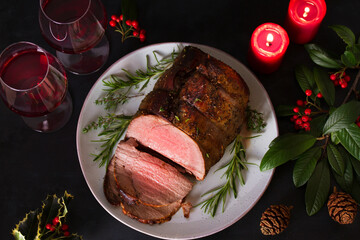 Whole round roast beef, red wine and Christmas decorations. New Year dinner table. High angle view