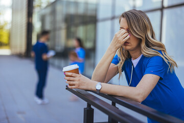 Tired Nurse Resting Outdoors Holding a Coffee Cup