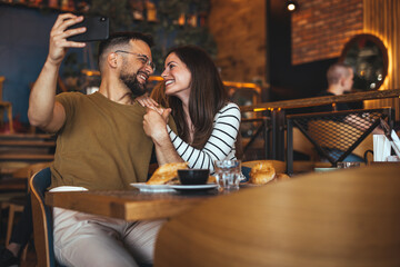 Couple Joyfully Taking Selfie Together in Cozy Café Setting