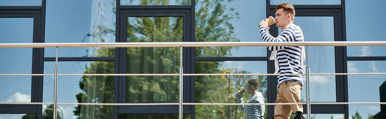 A young man with a prosthetic leg savors his coffee while standing outside a stylish structure.