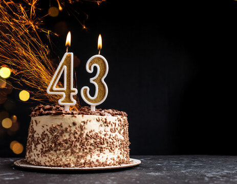 Birthday cake with 43 years birthday candles with sparks on dark background with copy space	