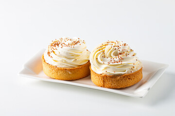 Lemon tartlets with whipped cream, sprinkles and chocolate chips on white background