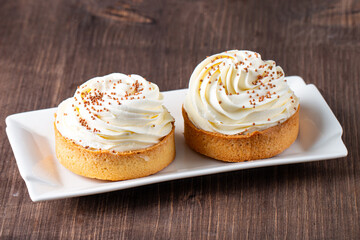 Lemon tartlets with whipped cream, sprinkles and chocolate chips on white background