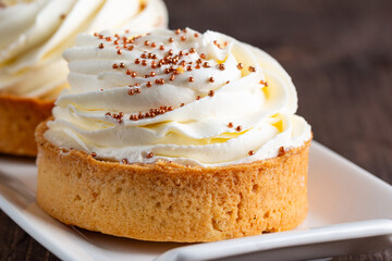 Lemon tartlets with whipped cream, sprinkles and chocolate chips on white background