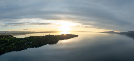 Fototapeta premium Dramatic panorama landscape of peninsula by calm waters of a lake at sunset