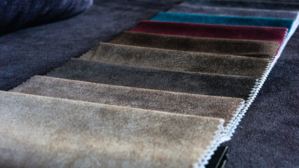 Fabric samples for furniture are lying on a sofa in a furniture store.