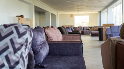 A spacious furniture store is bathed in sunlight, showcasing sofas.