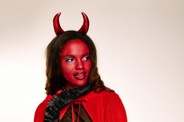 A captivating woman dressed as a devil captures attention with her striking red makeup and costume.