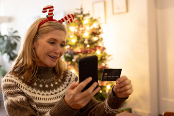 Christmas time, smiling senior woman shopping online with smartphone at home
