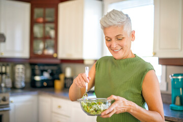 Mature smiling woman eating salad, fruits and vegetables.