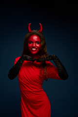 This striking woman in a red devil costume playfully poses, showcasing Halloween spirit.
