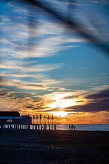 A breathtaking sunset casts vibrant colors over the ocean, with a pier