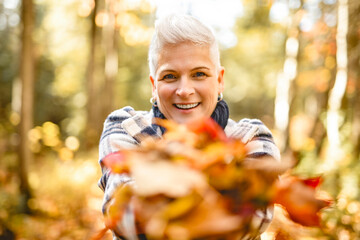 Mature woman in autumn forest, dressed in cozy fall attire, Reflection and connection with nature, wellness