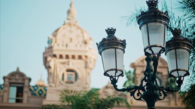 Close up of a street lamp with a blurry view of Monte Carlo Casino on the background