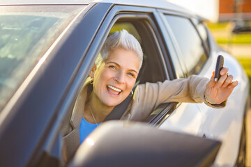 Happy owner. Handsome mature woman sitting relaxed in his newly bought car.