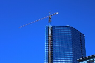 Glass building and crane, blue sky in the background.