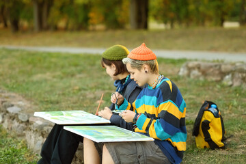two young and innovative female artists conducting an outdoor painting lesson. Surrounded by...