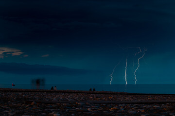 A spectacular lightning storm occurs above the ocean during the night