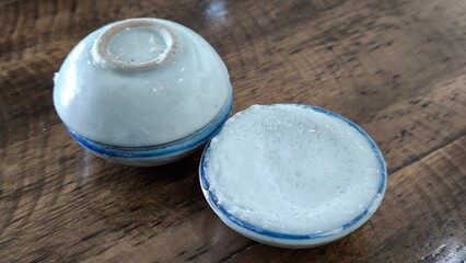 coconut milk custard in small porcelain cup (Thai dessert) in wooden dish on table.