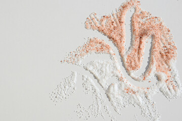 Common edible salt of white color and pink Himalayan salt on white background, copy space for text