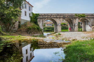 Three-arch bridge over the Alva river with house reflected in the moving water, Coja PORTUGAL