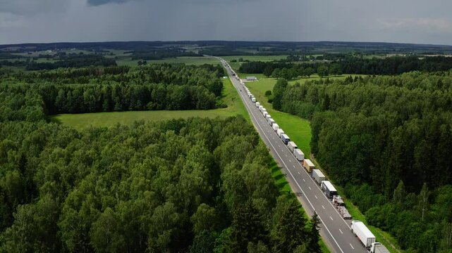 Large number of cargo trucks stuck in a long queue on a highway before a border post. Long queue of trucks.