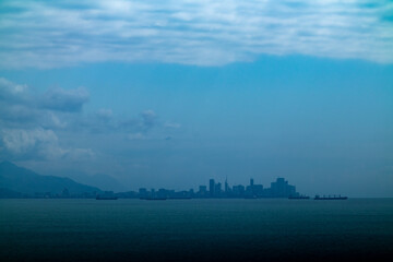 A blurry city skyline looms over the shimmering surface of the water