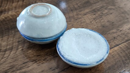 coconut milk custard in small porcelain cup (Thai dessert) in wooden dish on table.