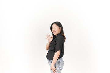 beautiful Asian woman smiles warmly, raising her hand in a friendly 'hi' gesture against a white background
