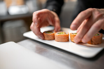 professional chef's hands making sushi roll in a restaurant kitchen