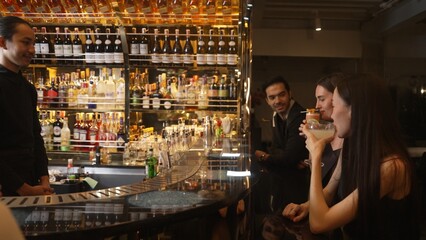 Couple talking at sitting bar with Margarita cocktail savoring sour tasty drink in happiness moment meeting while woman waiting friends at front view at luxurious counter vibrant nightclub. Vinosity.