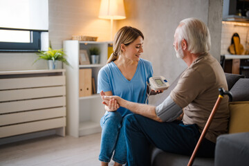 Caring Nurse Assisting Elderly Man With Blood Pressure Check