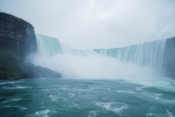 Fototapeta premium A magnificent waterfall plunges powerfully into a misty blue basin below, with towering rocky cliffs on each side, creating a breathtaking display of natural grandeur.