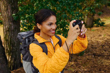 Joy radiates as a young woman captures the beauty of the autumn forest during her hike.