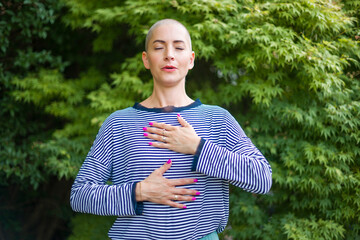 Young female cancer patient meditating doing breathing exercises in her garden. Mental health, life...