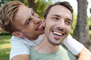 Obraz premium A cheerful couple embraces playfully under the warm sun in a lush park setting.