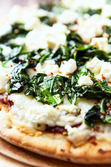 Pizza with mozzarella cheese and spinach. Dark wooden background. Close up.