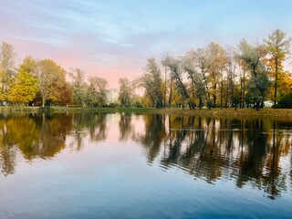 Beautiful tender twilights in the park, sky and trees reflection on the pond surface, evening lake in the park
