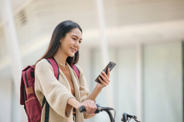 A woman is smiling while looking at her cell phone
